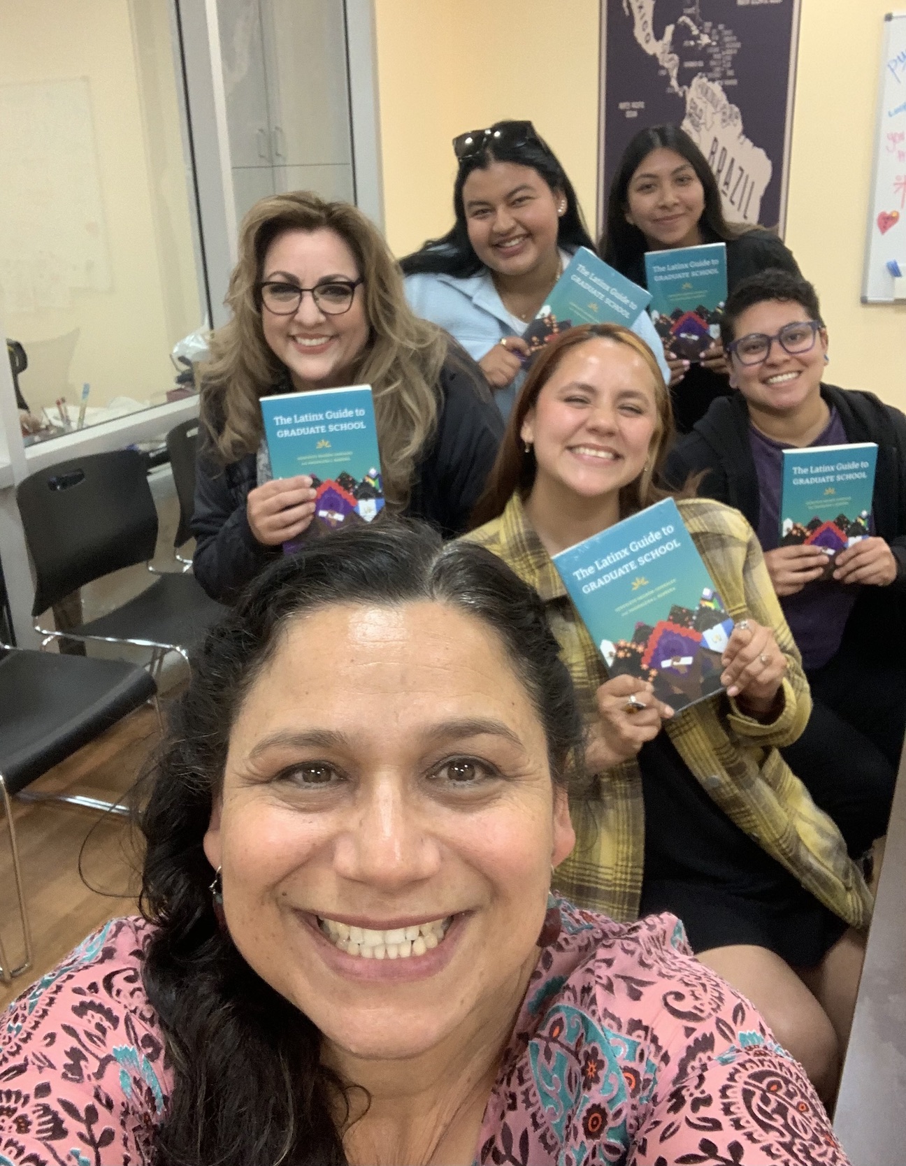 Irene Lara with students, holding Latinx Guide to Graduate School book.
